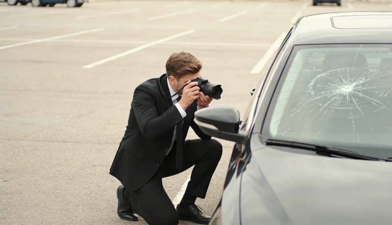 assureur photographiant pare brise fissure sur parking