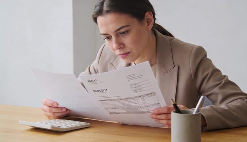 femme assise a un bureau examinant des fiches de paie