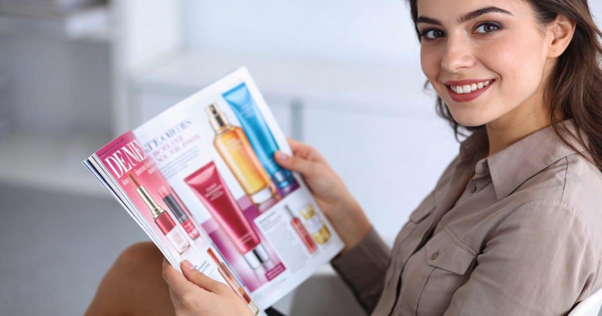 femme souriante feuilletant un magazine publicitaire coloré