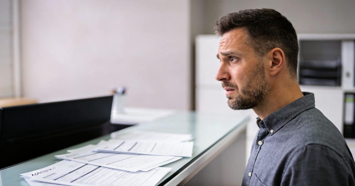 homme inquiet devant bureau administratif formulaires non remplis