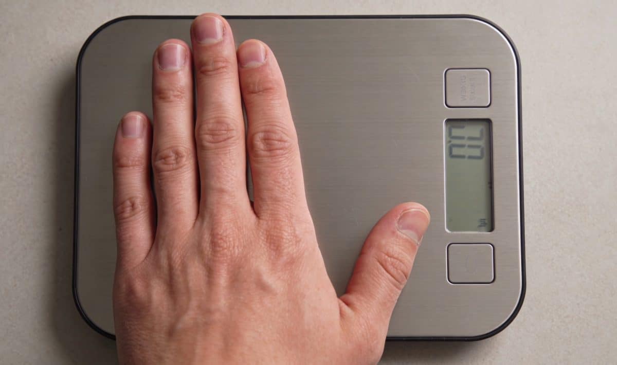 Main posant sur balance de cuisine numerique