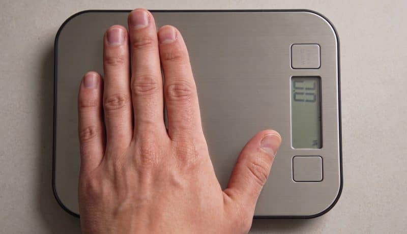 Main posant sur balance de cuisine numerique