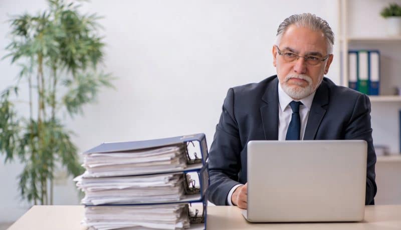 proprietaire assis devant bureau dossiers refuses empiles