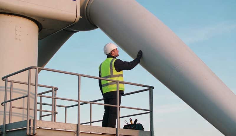 technicien inspectant pales d eoliennes sous ciel bleu