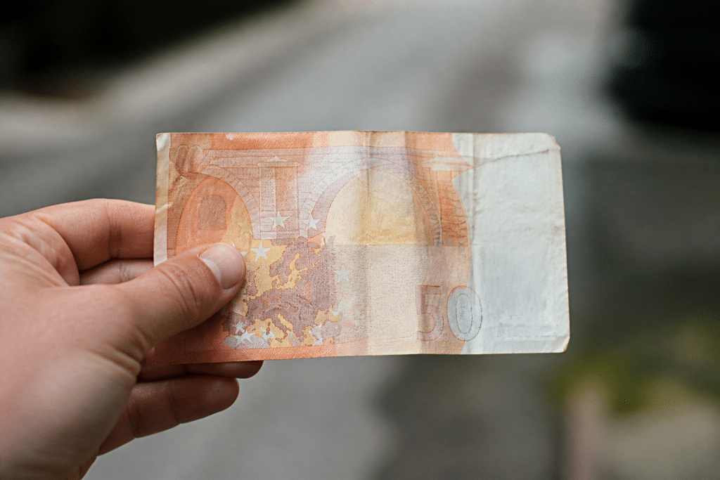 Ancien billet de cinquante euros tenu en main, arriere-plan flou.