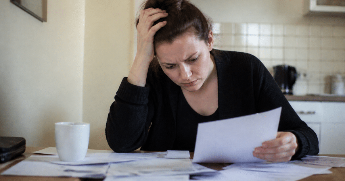 Personne anxieuse étudiant des documents financiers à table.