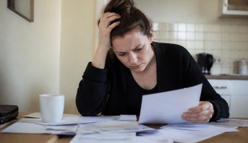Personne anxieuse étudiant des documents financiers à table.