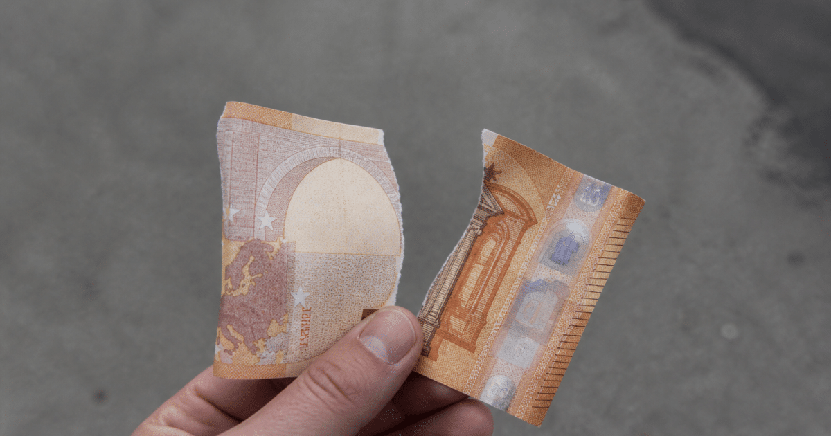 Billet de 50 euros dechire en deux morceaux.