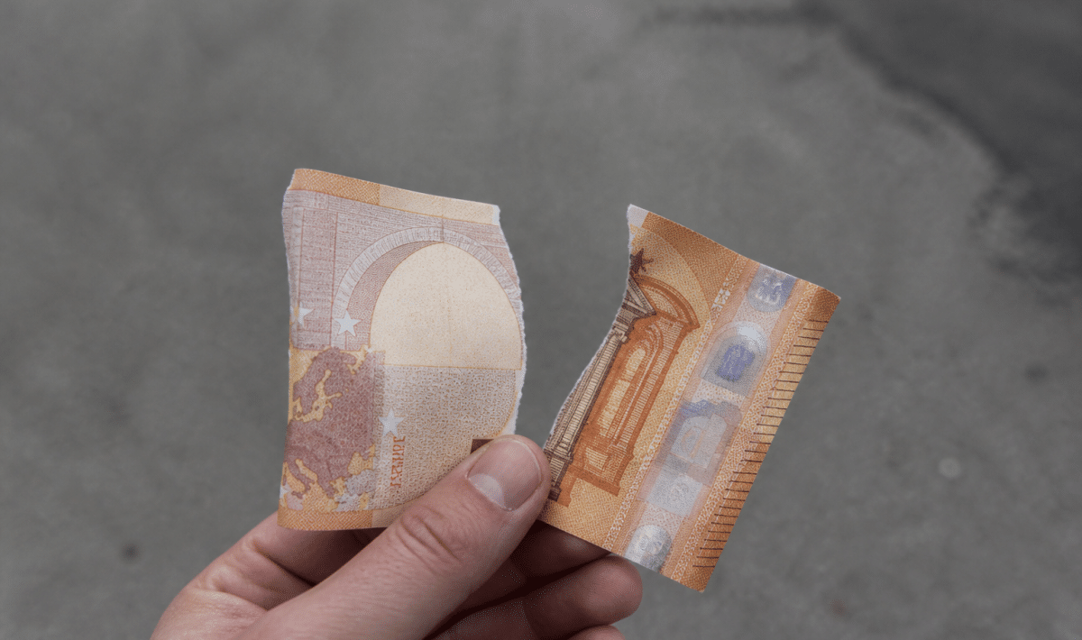 Billet de 50 euros dechire en deux morceaux.