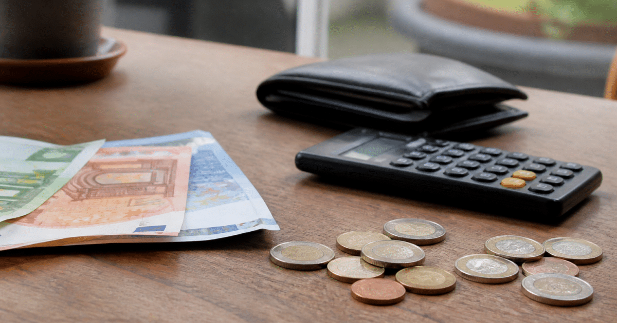 Billet de banque et pièces arrangés près d'une calculatrice.