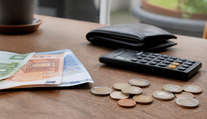 Billet de banque et pièces arrangés près d'une calculatrice.