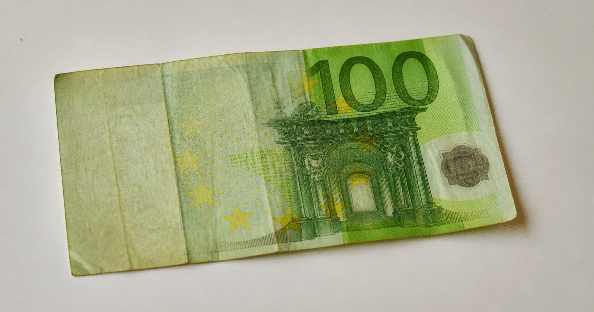 Billet de cent euros usé posé sur surface blanche.