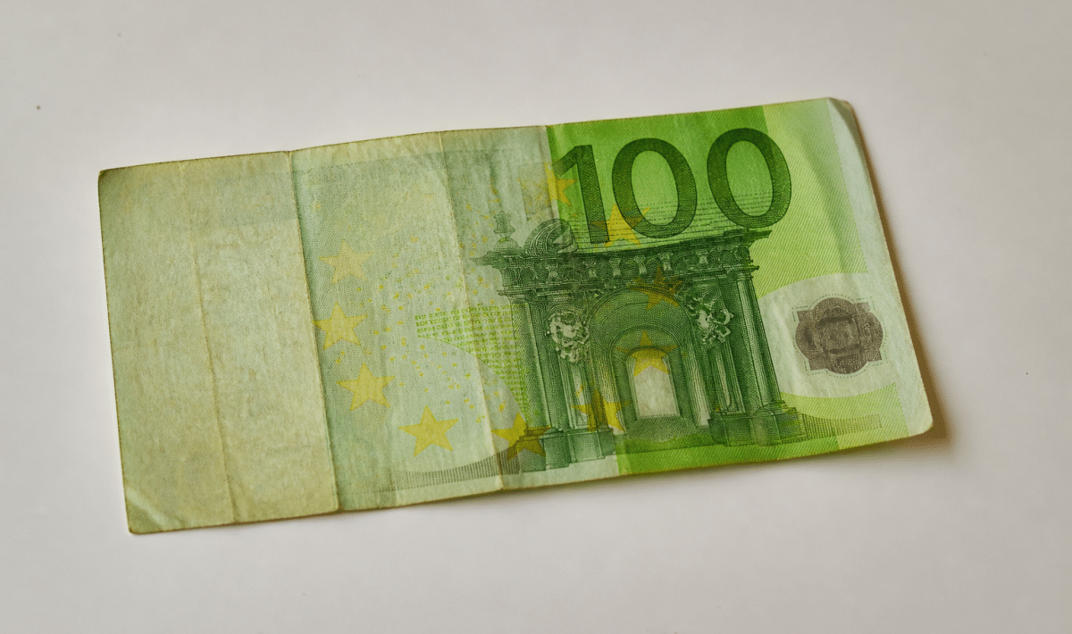 Billet de cent euros usé posé sur surface blanche.