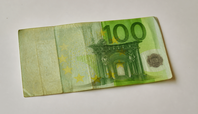 Billet de cent euros usé posé sur surface blanche.