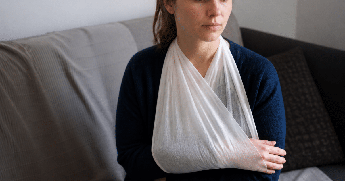 Bras immobilisé dans une écharpe blanche médicale.