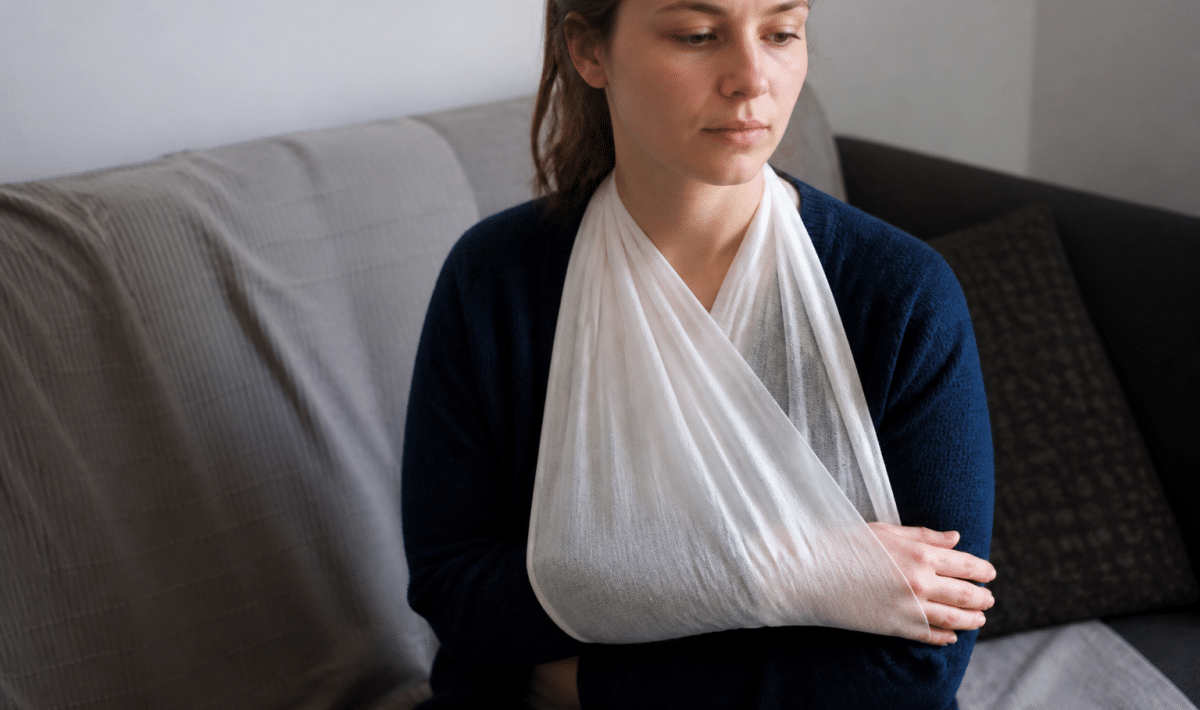 Bras immobilisé dans une écharpe blanche médicale.