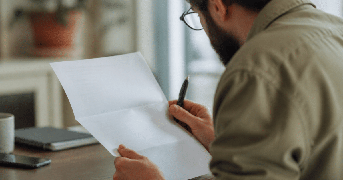 Document d'assurance avec stylo, mains consultant lisant attentivement.