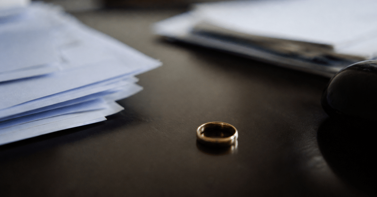 Documents financiers et anneau de mariage sur bureau sombre.