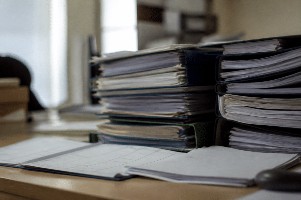 Dossiers administratifs empiles avec calendrier et contrats temporaires visibles.
