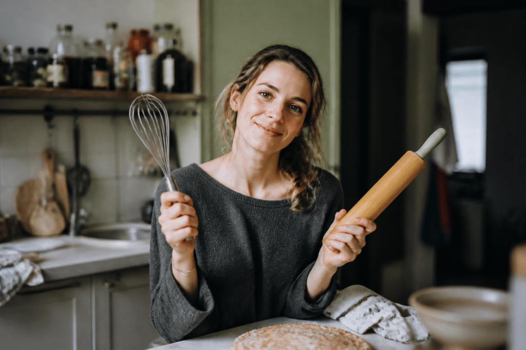 Femme en cuisine montrant ustensiles avec confiance et passion
