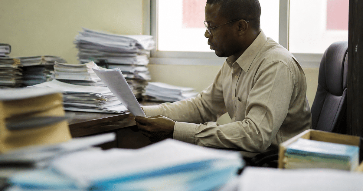Fonctionnaire assis a son bureau consultant documents officiels gouvernementaux.
