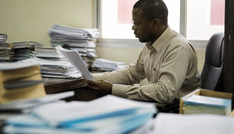 Fonctionnaire assis a son bureau consultant documents officiels gouvernementaux.