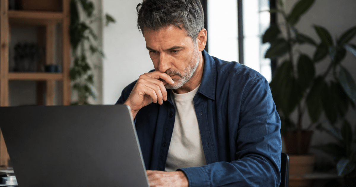 Homme consultant document financier sur ordinateur portable