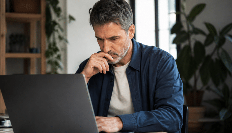 Homme consultant document financier sur ordinateur portable