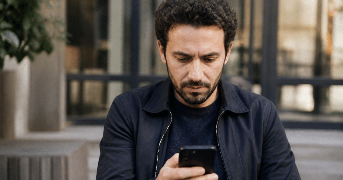 Homme consultant smartphone affichant interface reseau professionnel.