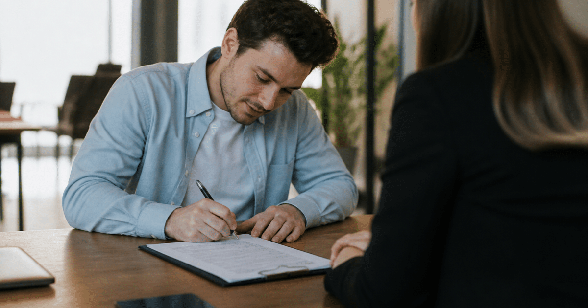Homme signe contrat CDI assis bureau face employeur