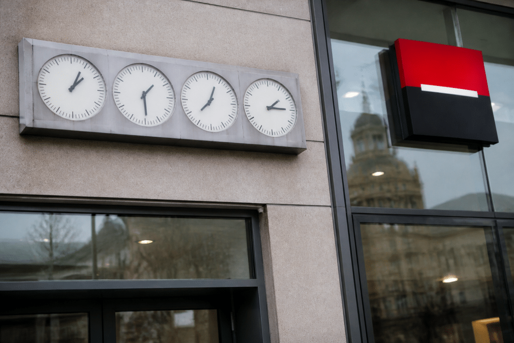 Horloge murale affichant differentes heures pres de logo bancaire