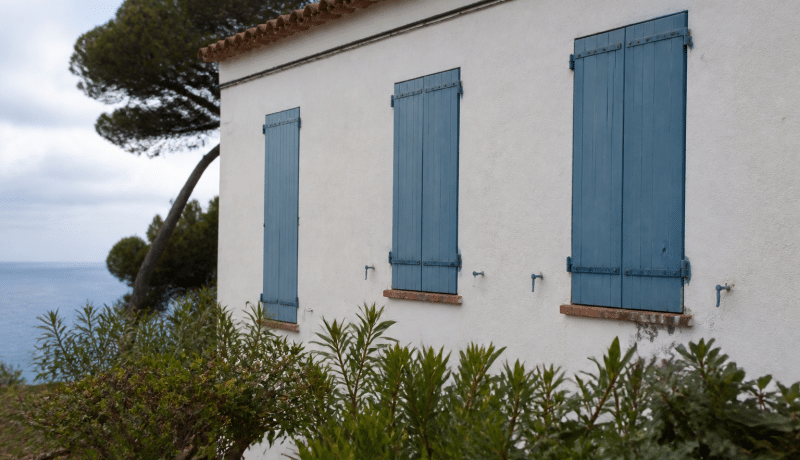 Maison côtière méditerranéenne avec volets bleus fermés