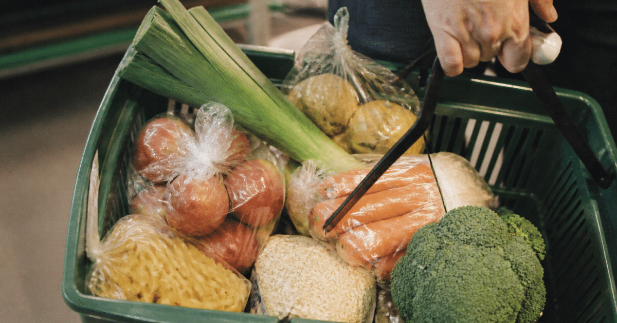 Panier d'epicerie avec legumes frais et paquets aliments economiques.