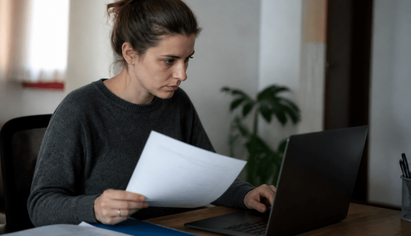 Personne assise devant ordinateur consultantdocuments administratifs emploi.