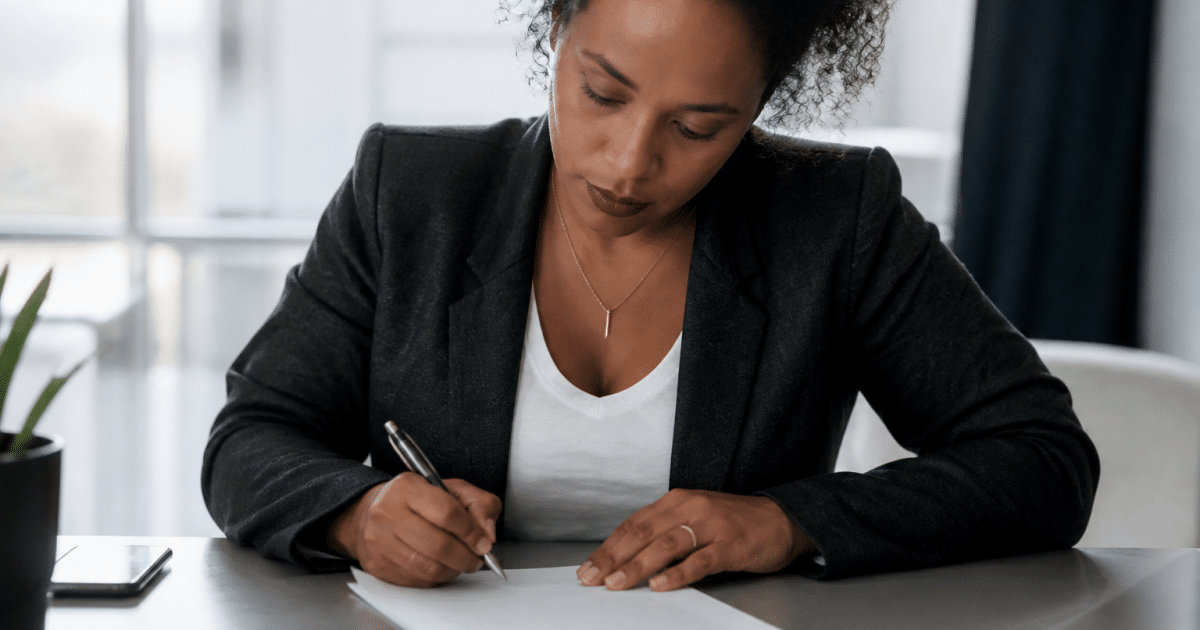 Personne assise a un bureau signant un document officiel
