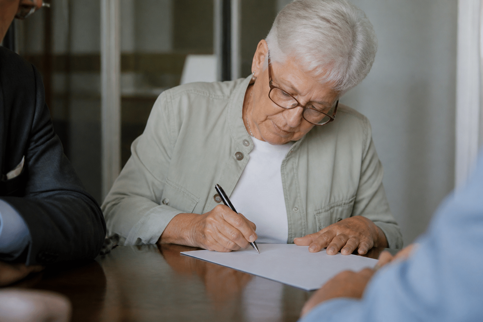 Personne âgée signant des documents notariés importants.